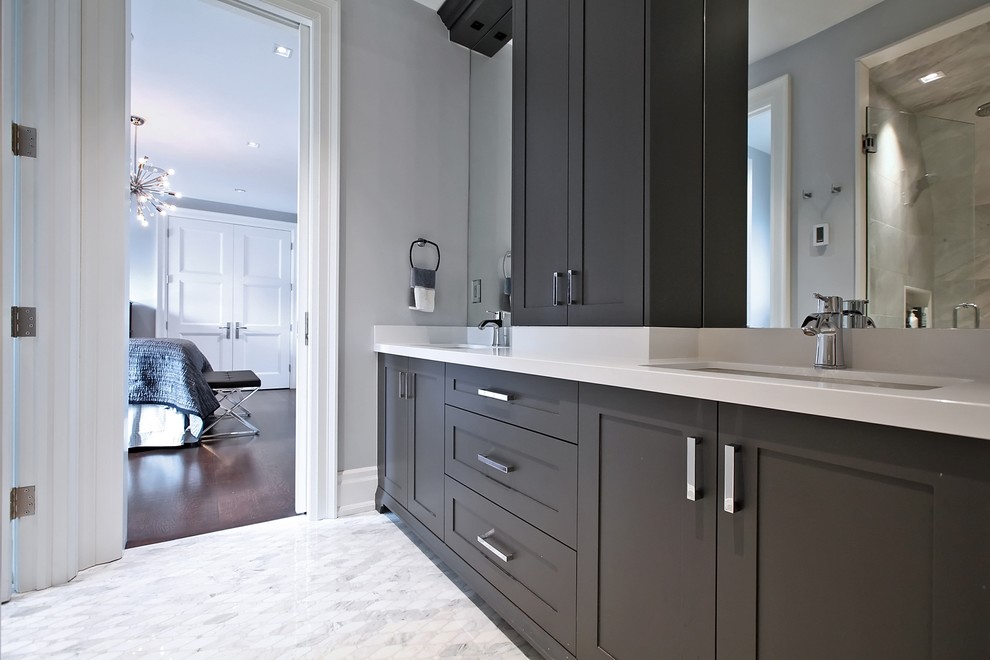 Photo of a mid-sized transitional master bathroom in Toronto with shaker cabinets, brown cabinets, an alcove shower, a two-piece toilet, gray tile, porcelain tile, grey walls, porcelain floors, an undermount sink, solid surface benchtops, white floor and a hinged shower door.