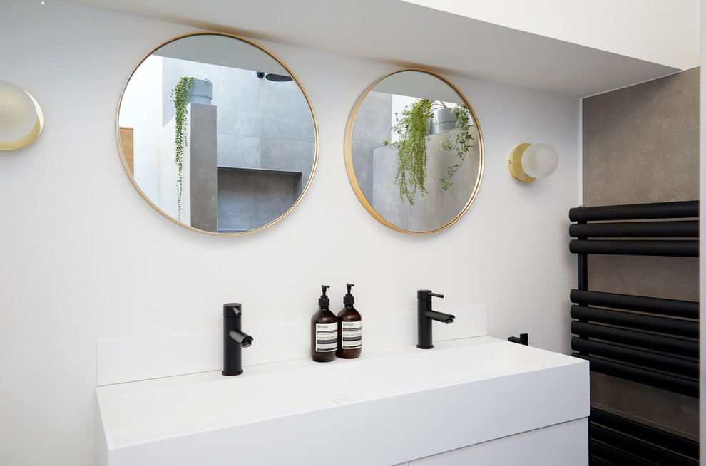 Photo of a small contemporary ensuite bathroom in London with flat-panel cabinets, white cabinets, a walk-in shower, a wall mounted toilet, porcelain tiles, grey walls, porcelain flooring, solid surface worktops, grey floors and an open shower.