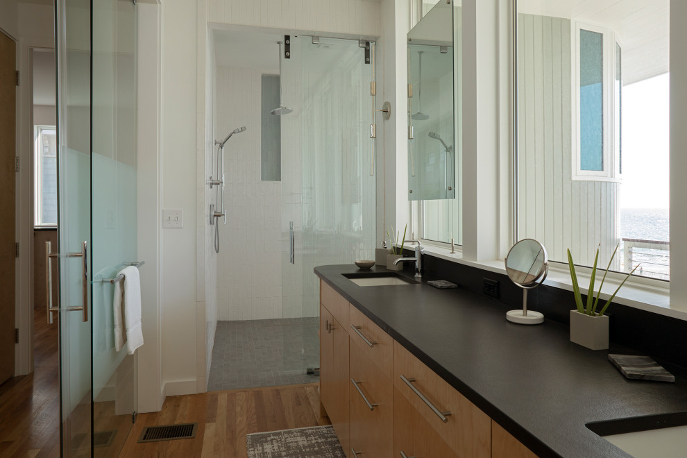 Exemple d'une salle de bain principale moderne en bois clair de taille moyenne avec un placard à porte plane, une baignoire indépendante, un combiné douche/baignoire, un mur blanc, un sol en bois brun, un lavabo encastré, un sol gris, une cabine de douche à porte battante, meuble double vasque et meuble-lavabo encastré.