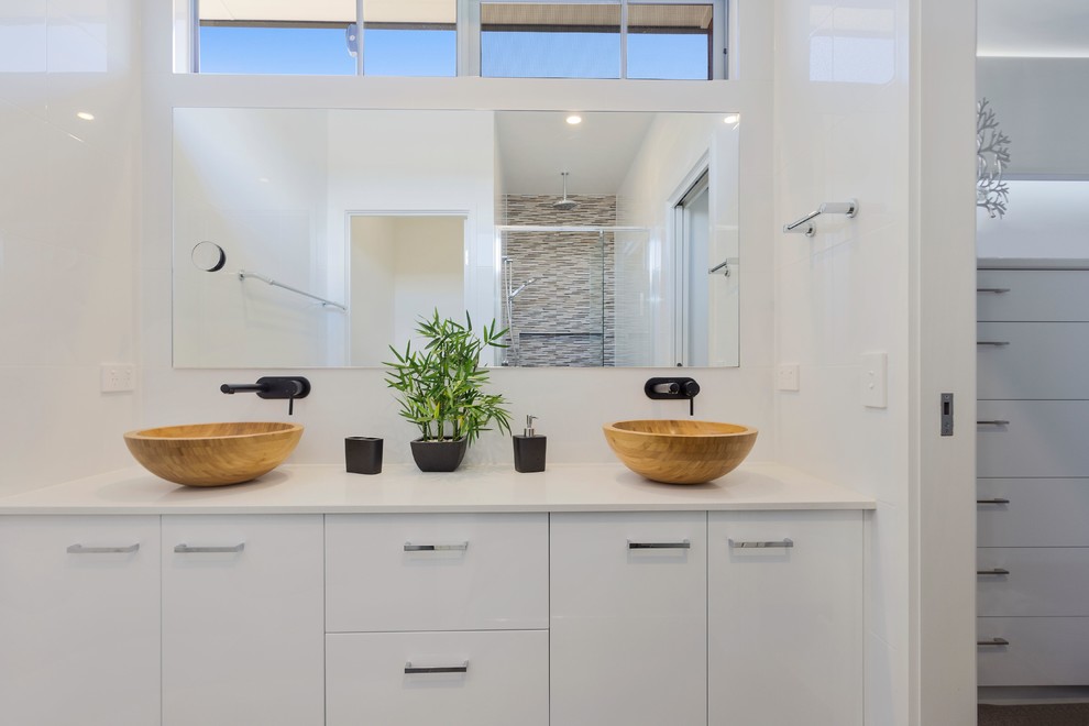 Пример оригинального дизайна: главная ванная комната среднего размера в стиле модернизм с плоскими фасадами, белыми фасадами, душем в нише, белой плиткой, керамической плиткой, белыми стенами, настольной раковиной и столешницей из искусственного кварца