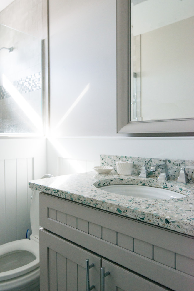 Inspiration för mellanstora moderna blått badrum med dusch, med skåp i shakerstil, vita skåp, en dusch i en alkov, en toalettstol med separat cisternkåpa, grå kakel, marmorkakel, ett undermonterad handfat, bänkskiva i återvunnet glas, dusch med gångjärnsdörr och beige väggar