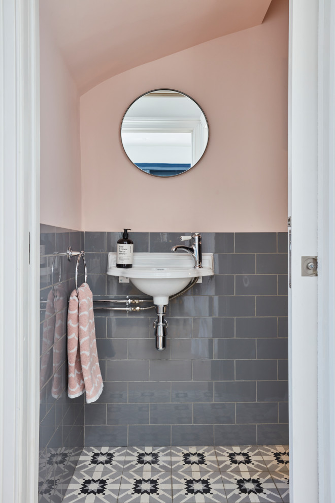 Inredning av ett eklektiskt mellanstort badrum för barn, med ett platsbyggt badkar, en öppen dusch, en vägghängd toalettstol, vit kakel, tunnelbanekakel, rosa väggar, cementgolv, ett piedestal handfat, grått golv och dusch med skjutdörr