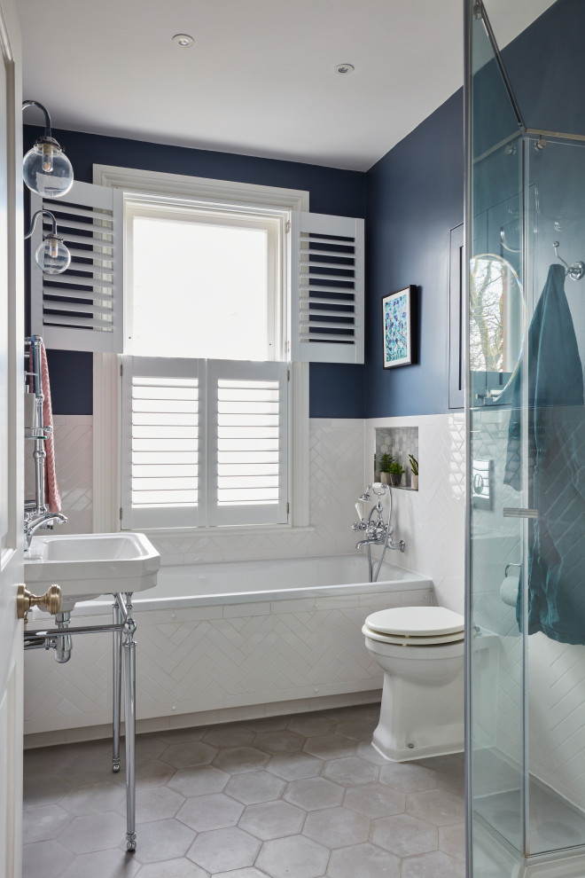 Inspiration for a medium sized classic family bathroom in Kent with a built-in bath, a walk-in shower, a wall mounted toilet, white tiles, porcelain tiles, blue walls, cement flooring, a pedestal sink, grey floors, a hinged door, a single sink and a freestanding vanity unit.