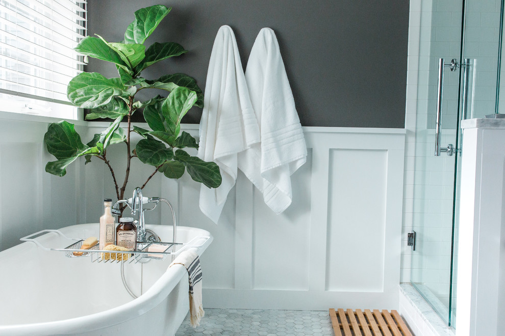 Cette photo montre une salle de bain principale éclectique de taille moyenne avec un placard à porte shaker, des portes de placard blanches, une baignoire sur pieds, une douche d'angle, WC séparés, un carrelage blanc, un carrelage métro, un mur gris, un sol en marbre, un plan de toilette en marbre et un lavabo encastré.