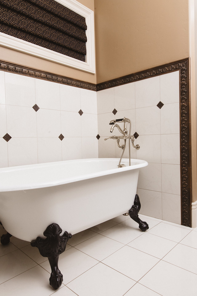 Идея дизайна: большая главная ванная комната в стиле кантри с фасадами с утопленной филенкой, темными деревянными фасадами, ванной на ножках, раздельным унитазом, черно-белой плиткой, керамогранитной плиткой, коричневыми стенами, полом из керамогранита, накладной раковиной и столешницей из гранита