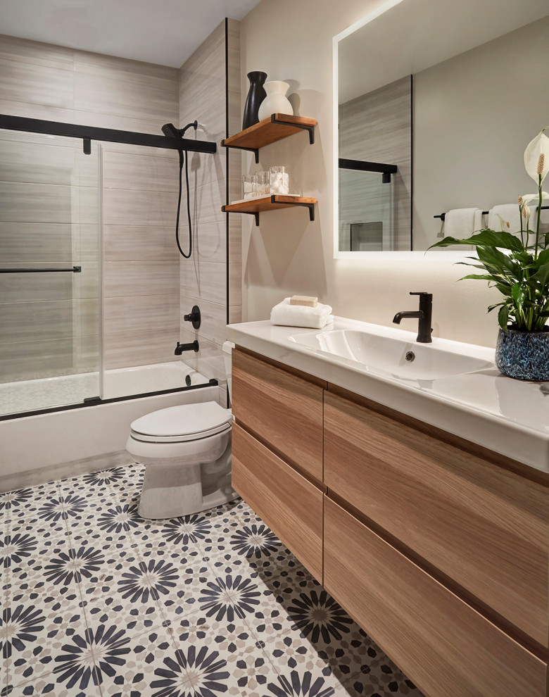 Exemple d'une petite salle de bain tendance en bois clair avec un placard à porte plane, une baignoire en alcôve, un combiné douche/baignoire, WC séparés, un carrelage gris, des carreaux de céramique, un mur gris, carreaux de ciment au sol, un lavabo suspendu, un sol bleu, une cabine de douche à porte coulissante, un plan de toilette blanc, une niche, meuble simple vasque et meuble-lavabo suspendu.