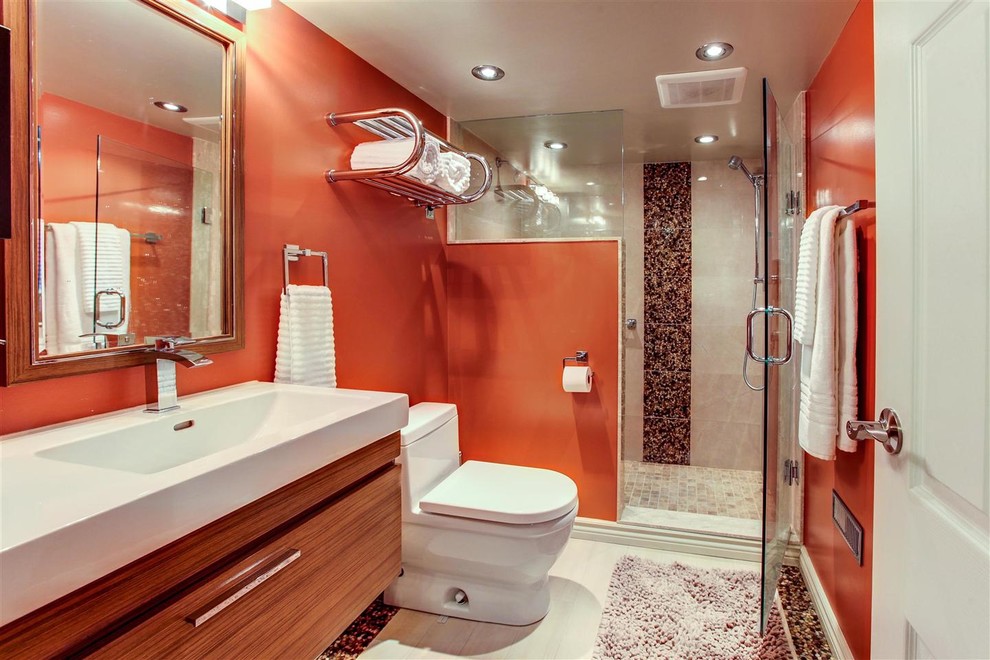 Ispirazione per una stanza da bagno con doccia design di medie dimensioni con ante lisce, ante in legno scuro, doccia doppia, WC monopezzo, pareti arancioni e top in superficie solida