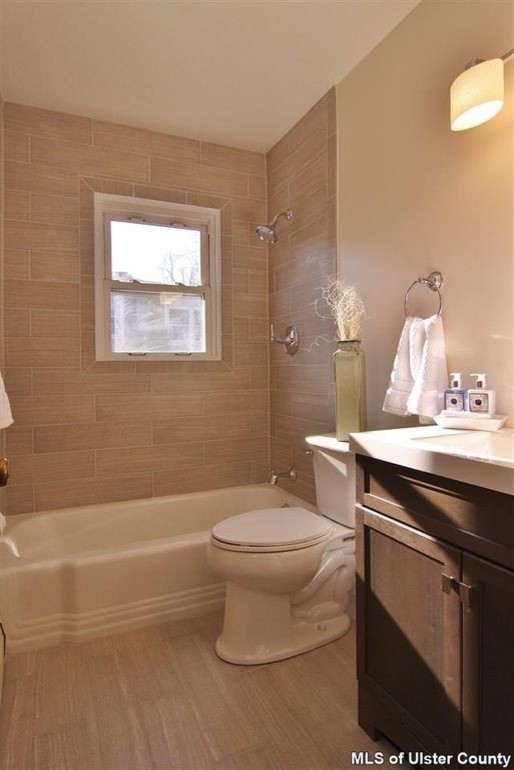 Idéer för ett litet modernt en-suite badrum, med släta luckor, skåp i mörkt trä, ett platsbyggt badkar, en dusch/badkar-kombination, en toalettstol med hel cisternkåpa, beige kakel, vita väggar, ljust trägolv och granitbänkskiva