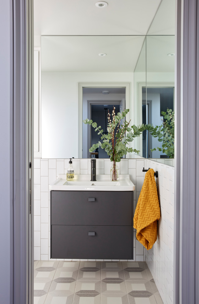Стильный дизайн: ванная комната среднего размера в стиле неоклассика (современная классика) с плоскими фасадами, серыми фасадами, белой плиткой, керамогранитной плиткой, полом из керамогранита, душевой кабиной, монолитной раковиной, серым полом, тумбой под одну раковину, подвесной тумбой, открытым душем, раздельным унитазом, белыми стенами и открытым душем - последний тренд