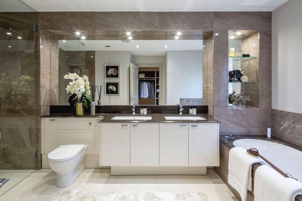 Inspiration for a large modern bathroom in Berkshire with flat-panel cabinets, white cabinets, a corner bath, a one-piece toilet, brown tiles, a submerged sink, white floors, an open shower and black worktops.