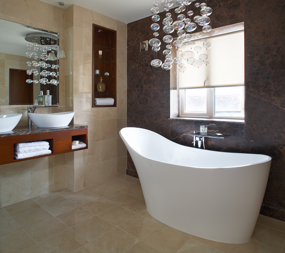 Contemporary bathroom in Dublin with a freestanding bath, stone slabs, a vessel sink and brown tiles.