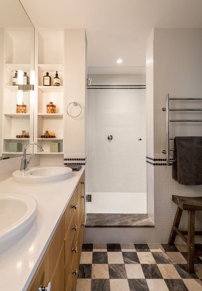 Photo of a large contemporary ensuite wet room bathroom in Sydney with a built-in sink, flat-panel cabinets, medium wood cabinets, white tiles, mosaic tiles, white walls, porcelain flooring, solid surface worktops, multi-coloured floors, an open shower and white worktops.