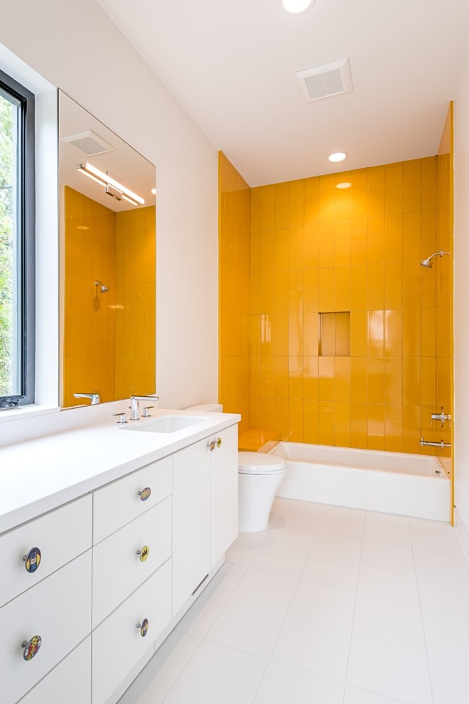 Стильный дизайн: ванная комната среднего размера в современном стиле с плоскими фасадами, белыми фасадами, ванной в нише, душем над ванной, унитазом-моноблоком, желтой плиткой, стеклянной плиткой, белыми стенами, полом из керамогранита, душевой кабиной, врезной раковиной и столешницей из искусственного камня - последний тренд
