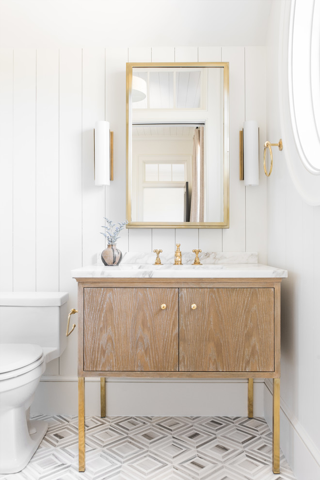 Modelo de cuarto de baño marinero con puertas de armario de madera clara, paredes blancas, lavabo bajoencimera, suelo multicolor, espejo con luz y armarios con paneles lisos