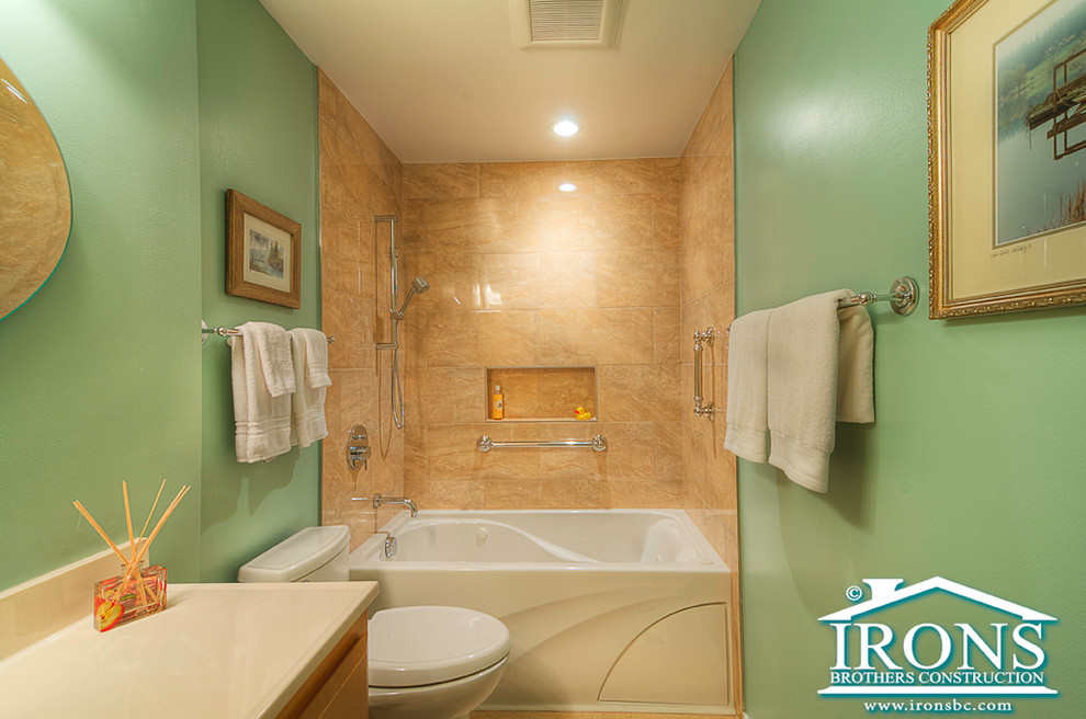 This is an example of a small traditional family bathroom in Seattle with beige tiles, stone tiles, green walls, porcelain flooring, an integrated sink, an alcove bath, a shower/bath combination and a one-piece toilet.