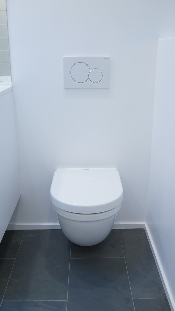 Photo of a small modern bathroom in Seattle with a wall mounted toilet, slate flooring and grey floors.