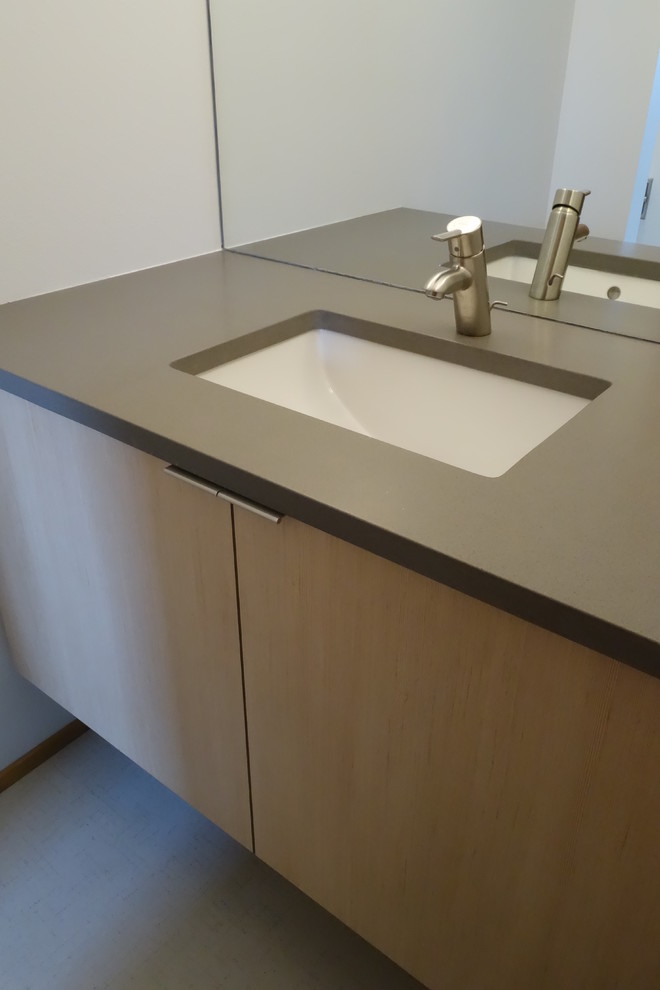 Cette image montre une salle de bain principale minimaliste de taille moyenne avec un lavabo encastré, un placard à porte plane, un plan de toilette en quartz modifié, WC séparés, un mur blanc et un sol en vinyl.