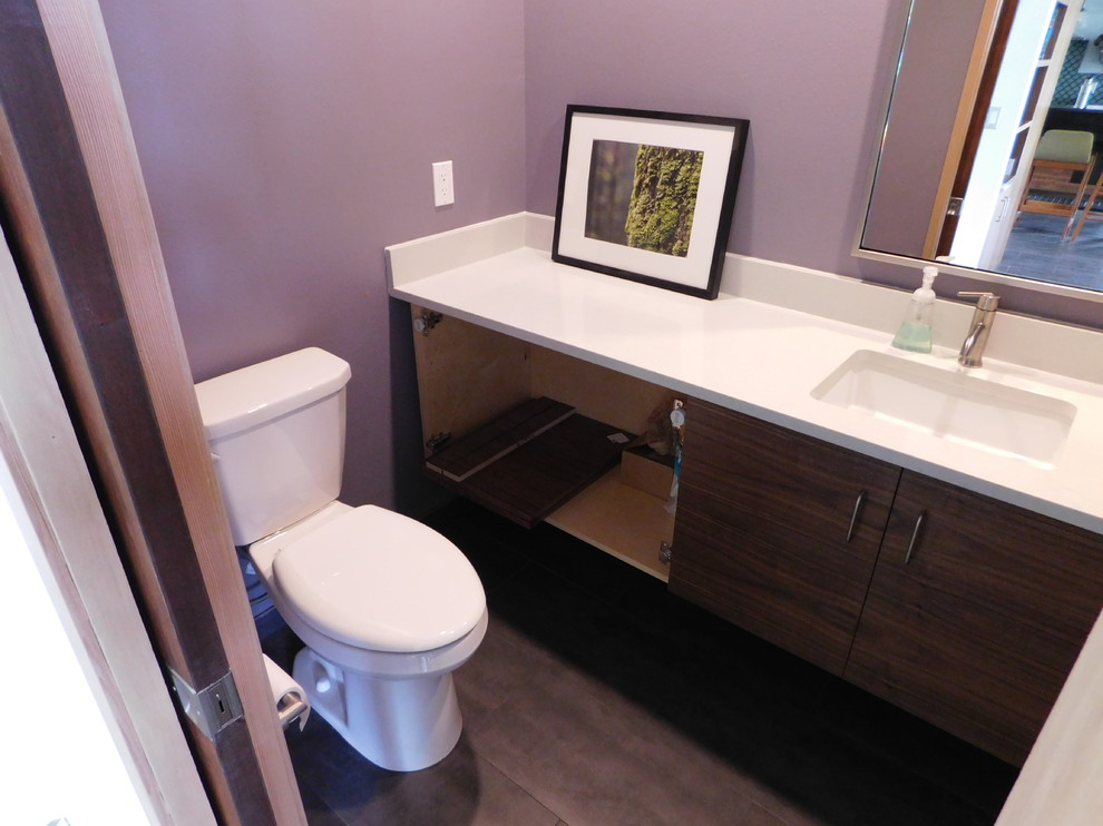 Immagine di una piccola stanza da bagno minimalista con ante lisce, ante in legno bruno, WC a due pezzi, piastrelle grigie, lavabo sottopiano, top in quarzo composito e pareti viola