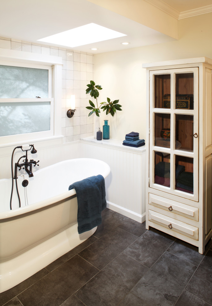 Пример оригинального дизайна: большая главная ванная комната в стиле неоклассика (современная классика) с фасадами с утопленной филенкой, коричневыми фасадами, отдельно стоящей ванной, душем без бортиков, унитазом-моноблоком, белой плиткой, керамогранитной плиткой, бежевыми стенами, полом из керамогранита, врезной раковиной, мраморной столешницей, серым полом, душем с раздвижными дверями, белой столешницей, нишей, тумбой под две раковины, напольной тумбой и панелями на стенах
