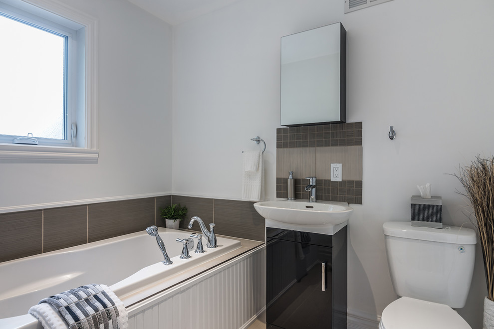 Photo of a medium sized contemporary bathroom in Montreal with a trough sink, flat-panel cabinets, grey cabinets, granite worktops, a built-in bath, an alcove shower, a two-piece toilet, multi-coloured tiles, porcelain tiles, white walls and porcelain flooring.