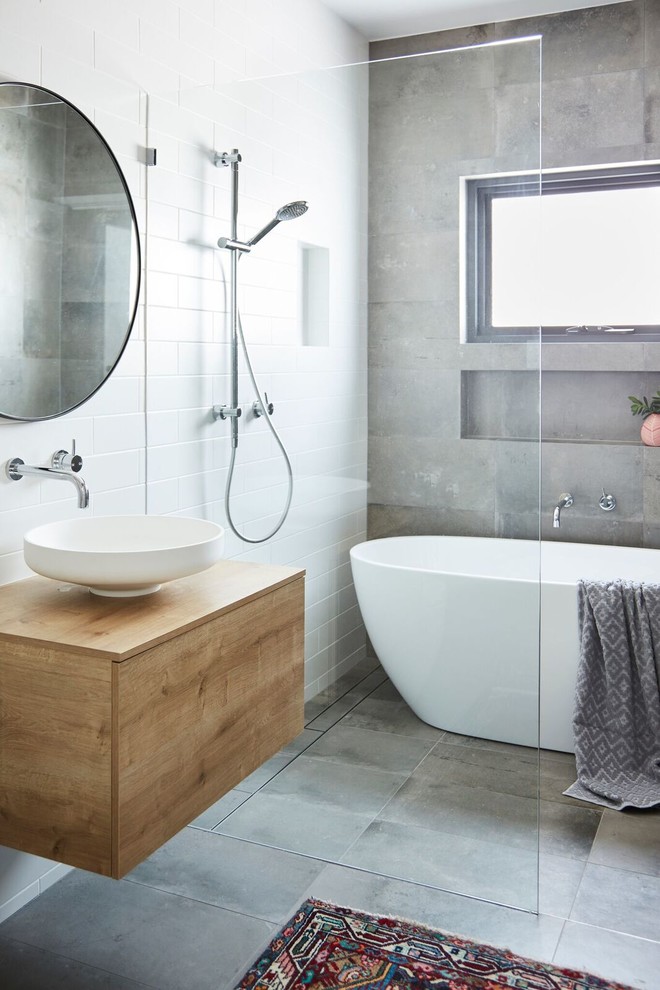 Photo of a contemporary bathroom in Sydney with freestanding cabinets, light wood cabinets, a freestanding bath, a wall mounted toilet, multi-coloured tiles, cement tiles, laminate worktops and an open shower.