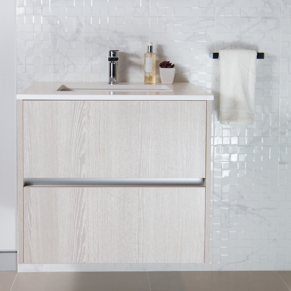 Cette image montre une salle de bain design en bois clair avec un placard à porte plane, du carrelage en marbre, un mur blanc, un lavabo encastré et un plan de toilette en quartz modifié.