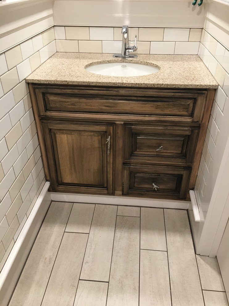 Example of a small trendy white tile and ceramic tile ceramic tile and beige floor bathroom design in Boston with raised-panel cabinets, distressed cabinets, a one-piece toilet, brown walls, an undermount sink and granite countertops