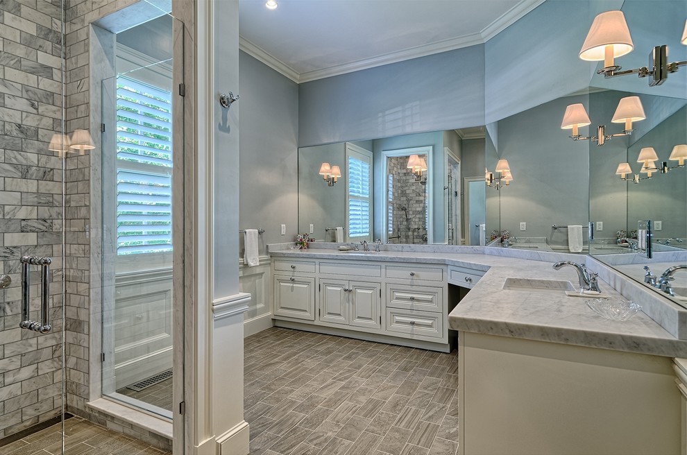 Large transitional master gray tile and stone tile laminate floor and gray floor alcove shower photo in New York with raised-panel cabinets, white cabinets, blue walls, an undermount sink, marble countertops and a hinged shower door