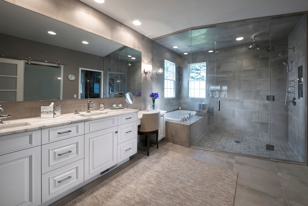 Klassisk inredning av ett en-suite badrum, med luckor med upphöjd panel, vita skåp, ett platsbyggt badkar, en kantlös dusch, grå kakel, ett undermonterad handfat, marmorbänkskiva och dusch med gångjärnsdörr