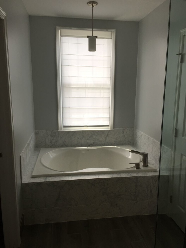 Large elegant master gray tile and stone tile brown floor drop-in bathtub photo in Detroit with gray walls