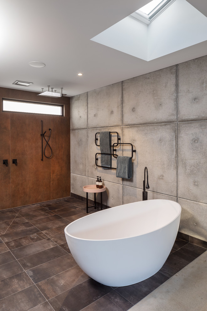Foto på ett stort industriellt en-suite badrum, med släta luckor, bruna skåp, ett fristående badkar, en öppen dusch, flerfärgad kakel, flerfärgade väggar, klinkergolv i keramik, ett väggmonterat handfat, brunt golv och med dusch som är öppen