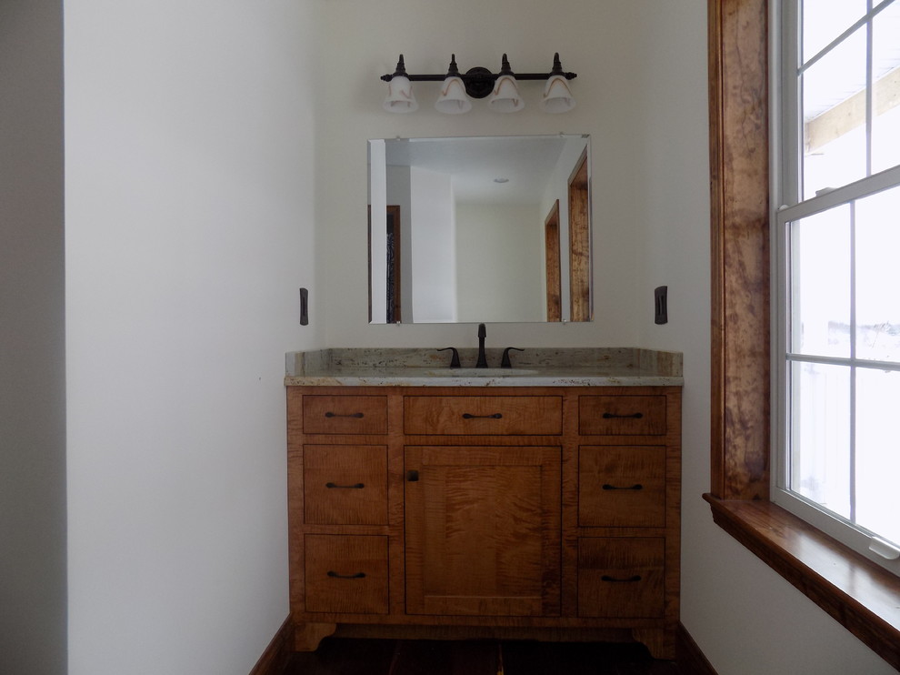 Imagen de cuarto de baño principal tradicional de tamaño medio con lavabo bajoencimera, armarios con paneles lisos, puertas de armario de madera oscura, encimera de granito, paredes blancas y suelo de madera en tonos medios