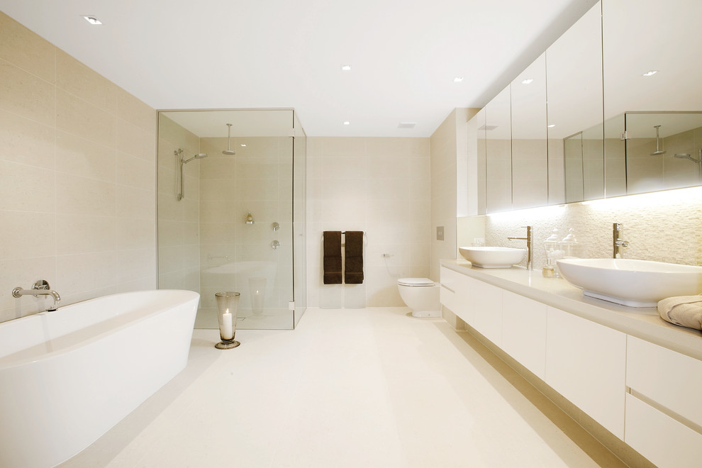 Inspiration for a contemporary bathroom in Melbourne with flat-panel cabinets, white cabinets, a freestanding bath, a corner shower, a one-piece toilet, beige walls, a vessel sink and a hinged door.