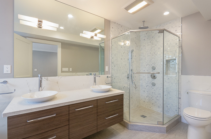 Inspiration for a medium sized contemporary ensuite bathroom in San Francisco with a vessel sink, flat-panel cabinets, medium wood cabinets, a corner shower, a one-piece toilet, grey walls, ceramic flooring, grey tiles, white tiles, porcelain tiles, engineered stone worktops, grey floors, a hinged door and a freestanding bath.