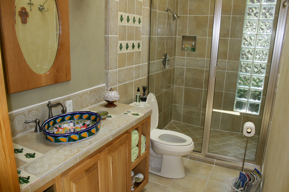 Источник вдохновения для домашнего уюта: маленькая ванная комната в средиземноморском стиле с фасадами с выступающей филенкой, фасадами цвета дерева среднего тона, душем в нише, раздельным унитазом, бежевой плиткой, керамической плиткой, бежевыми стенами, полом из керамической плитки, душевой кабиной, настольной раковиной, столешницей из плитки, бежевым полом и душем с распашными дверями для на участке и в саду