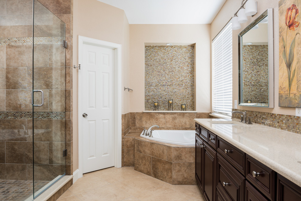 Пример оригинального дизайна: главная ванная комната среднего размера в современном стиле с фасадами с филенкой типа жалюзи, коричневыми фасадами, угловой ванной, душем в нише, унитазом-моноблоком, разноцветной плиткой, плиткой мозаикой, бежевыми стенами, полом из керамогранита, монолитной раковиной, мраморной столешницей, бежевым полом и душем с распашными дверями