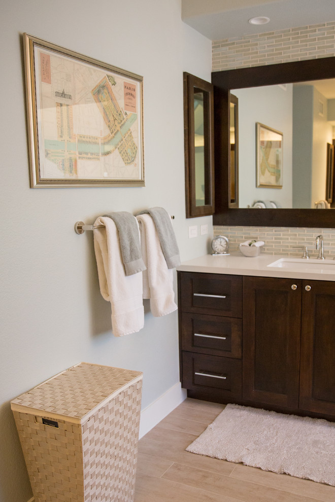 Photo of a large contemporary ensuite bathroom in San Diego with an integrated sink, beaded cabinets, dark wood cabinets, limestone worktops, a built-in bath, an alcove shower, a one-piece toilet, grey tiles, grey walls and light hardwood flooring.