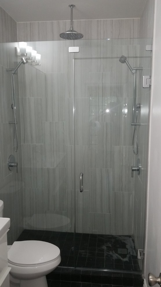 Inspiration for a mid-sized contemporary master ceramic tile and black floor alcove shower remodel in Austin with flat-panel cabinets, white cabinets, gray walls, a hinged shower door and a two-piece toilet