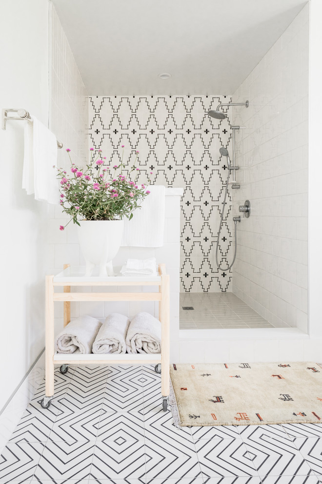 Inredning av ett modernt badrum, med en dusch i en alkov, svart och vit kakel, vita väggar, cementgolv, flerfärgat golv och med dusch som är öppen