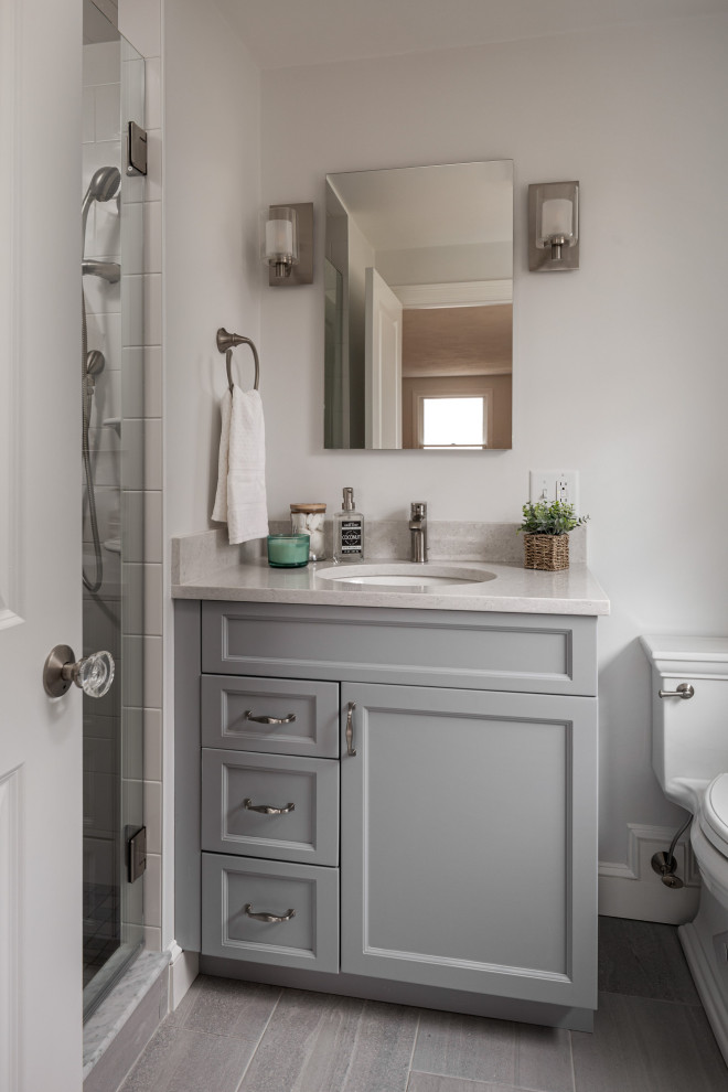 Design ideas for a small classic ensuite bathroom in Boston with flat-panel cabinets, grey cabinets, an alcove shower, a two-piece toilet, multi-coloured tiles, glass tiles, grey walls, a submerged sink, engineered stone worktops, grey floors, a hinged door, white worktops, a wall niche, a single sink and a built in vanity unit.