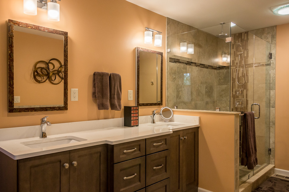 Пример оригинального дизайна: главная ванная комната среднего размера в стиле кантри с фасадами в стиле шейкер, фасадами цвета дерева среднего тона, полом из керамической плитки, душем в нише, бежевой плиткой, керамической плиткой, оранжевыми стенами, подвесной раковиной, столешницей из искусственного кварца, коричневым полом, душем с распашными дверями и белой столешницей