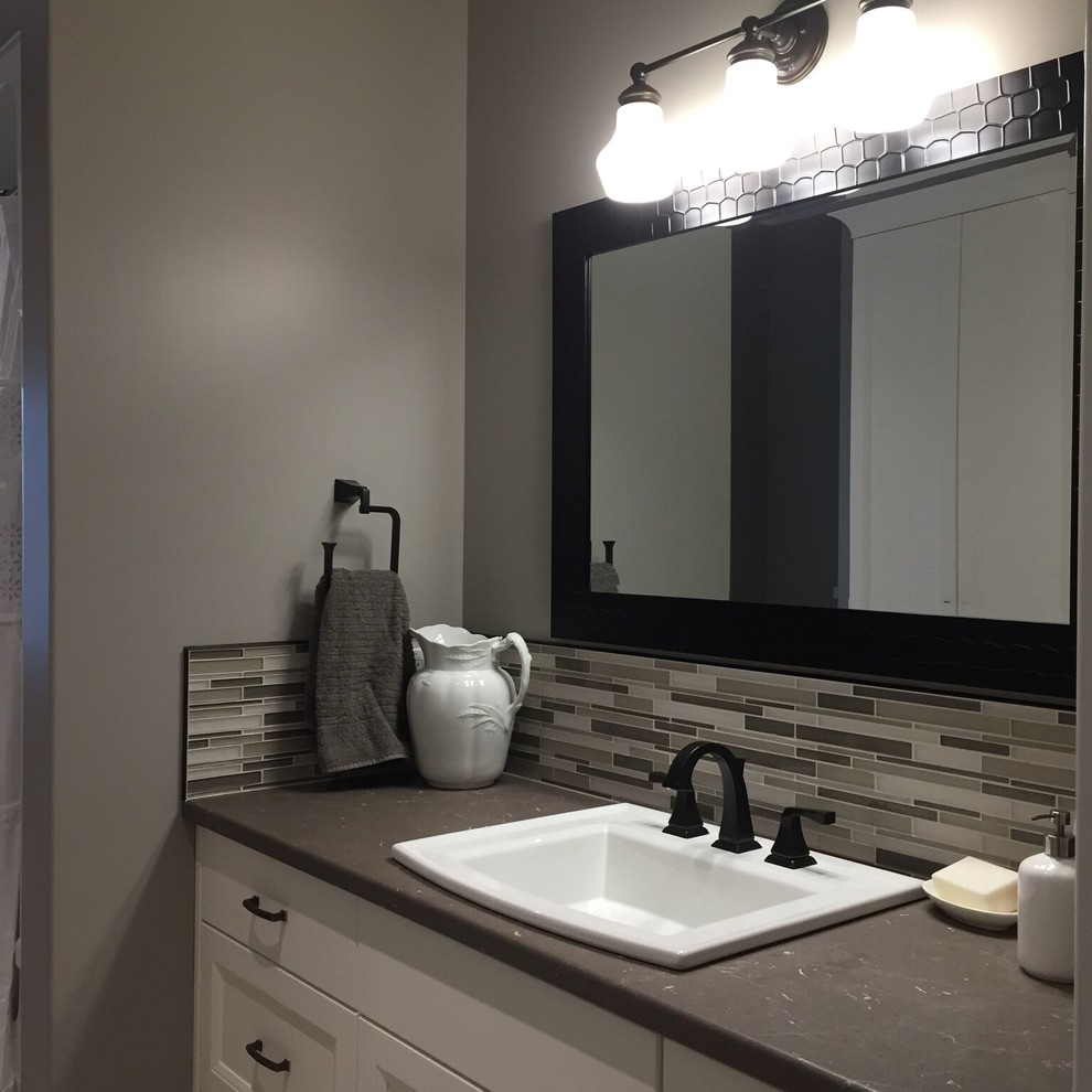 This is an example of a medium sized traditional bathroom in Toronto with recessed-panel cabinets, white cabinets, multi-coloured tiles, matchstick tiles, grey walls, a built-in sink, solid surface worktops and grey worktops.