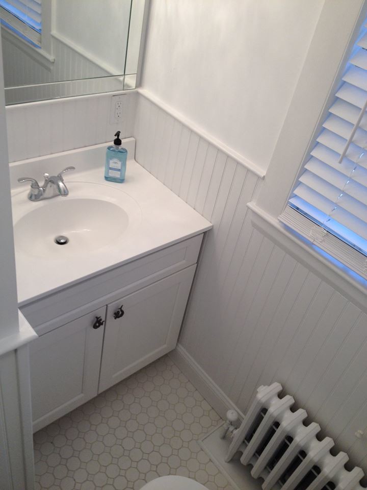 Inredning av ett klassiskt litet badrum med dusch, med luckor med infälld panel, vita skåp, vita väggar och ett integrerad handfat