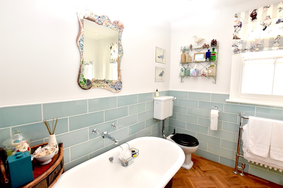 Maritimes Badezimmer mit freistehender Badewanne, offener Dusche, Toilette mit Aufsatzspülkasten, grünen Fliesen, dunklem Holzboden, Wandwaschbecken und Schiebetür-Duschabtrennung in Sonstige