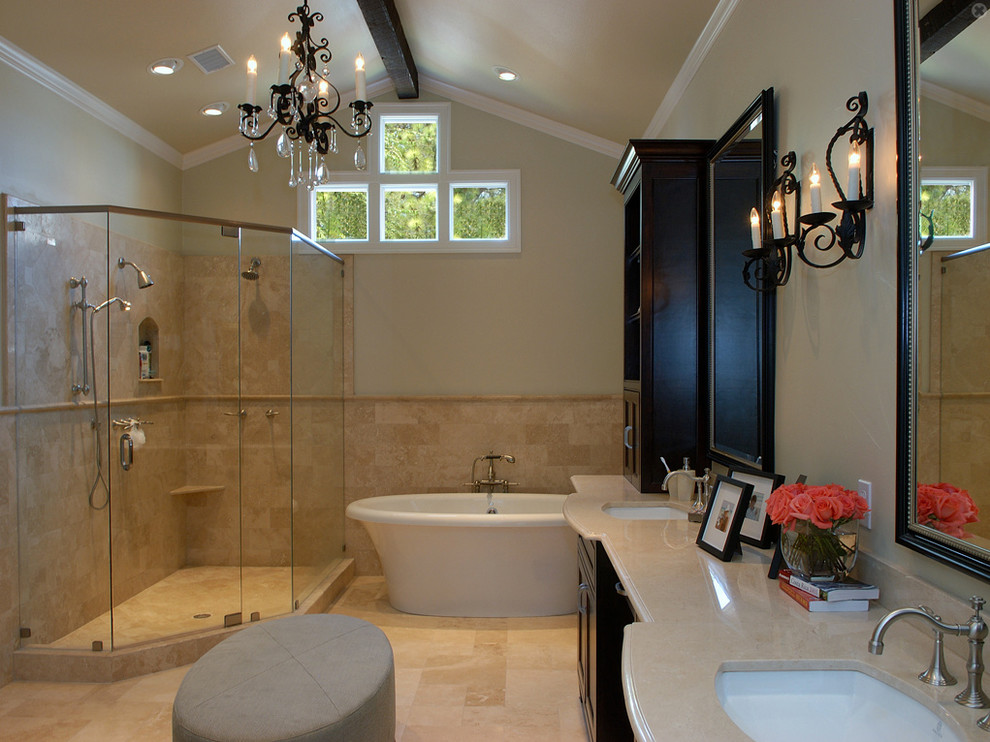 ダラスにある中くらいなトラディショナルスタイルのおしゃれなマスターバスルーム (オーバーカウンターシンク、落し込みパネル扉のキャビネット、黒いキャビネット、ライムストーンの洗面台、置き型浴槽、コーナー設置型シャワー、一体型トイレ	、白いタイル、白い壁、ライムストーンの床) の写真