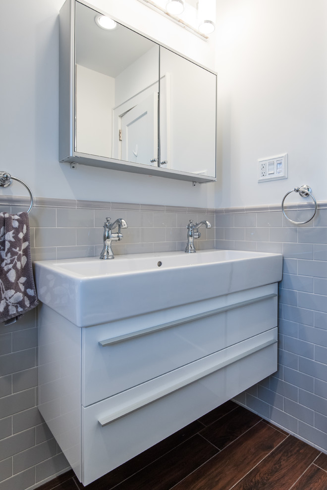 This is an example of a medium sized modern ensuite bathroom in Atlanta with flat-panel cabinets, white cabinets, an alcove bath, a shower/bath combination, a two-piece toilet, grey tiles, metro tiles, white walls, dark hardwood flooring and an integrated sink.