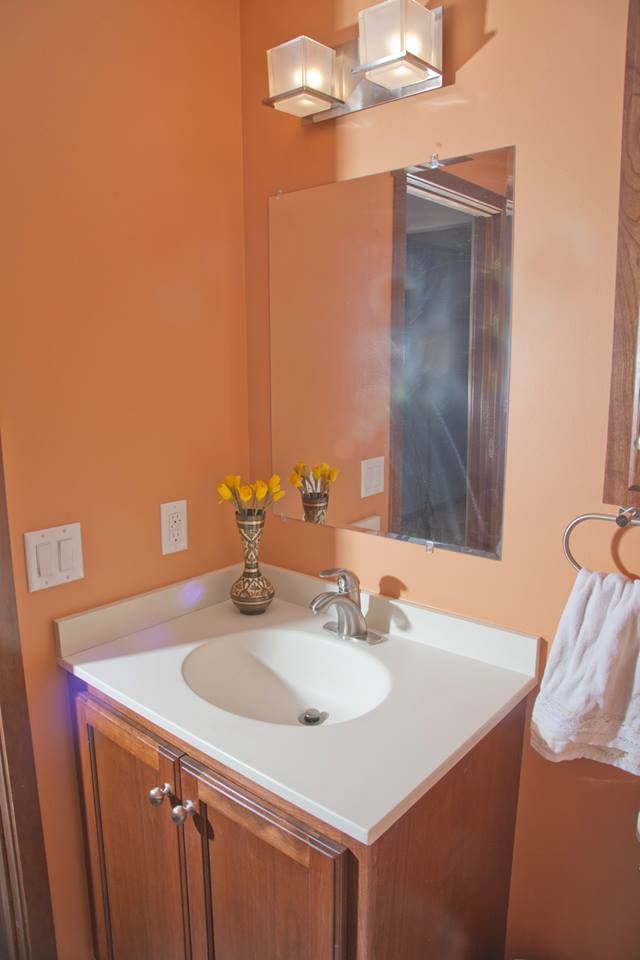 Small transitional bathroom photo in Minneapolis with medium tone wood cabinets, orange walls, shaker cabinets, an integrated sink and quartz countertops