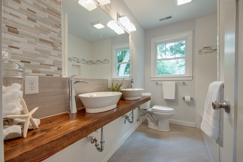 チャールストンにあるビーチスタイルのおしゃれな浴室 (ベッセル式洗面器、木製洗面台、アルコーブ型浴槽、分離型トイレ) の写真
