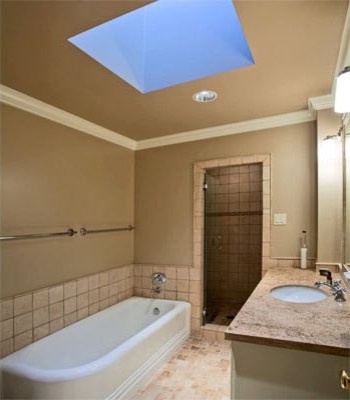 Modelo de cuarto de baño principal rural de tamaño medio con lavabo bajoencimera, puertas de armario blancas, encimera de granito, bañera esquinera, baldosas y/o azulejos de piedra, paredes beige y baldosas y/o azulejos beige