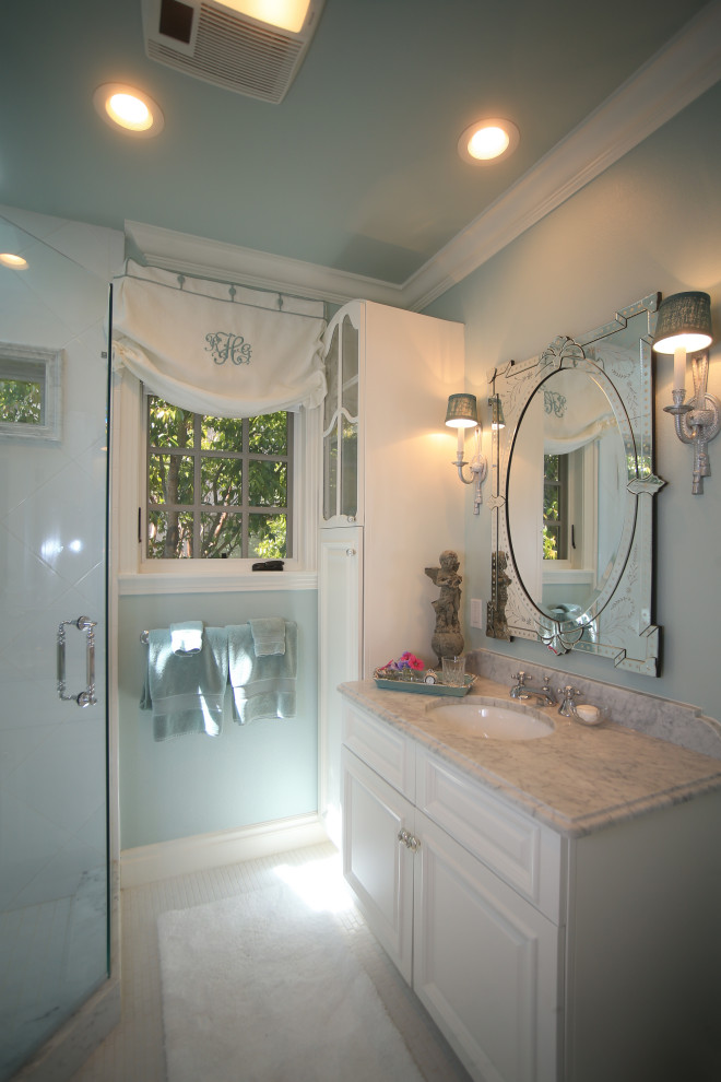 Example of a mid-sized classic 3/4 green tile marble floor and white floor corner shower design in Austin with glass-front cabinets, white cabinets, a one-piece toilet, green walls, an undermount sink, marble countertops, a hinged shower door and white countertops
